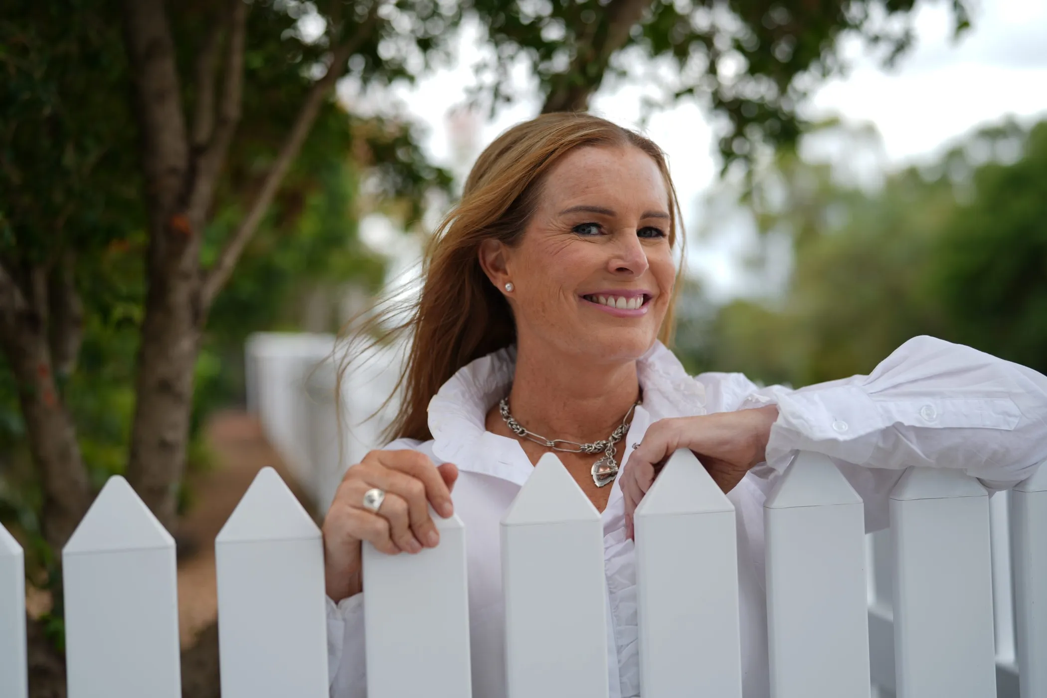 Brooke Seabrook smiling, leaning on a white picket fence